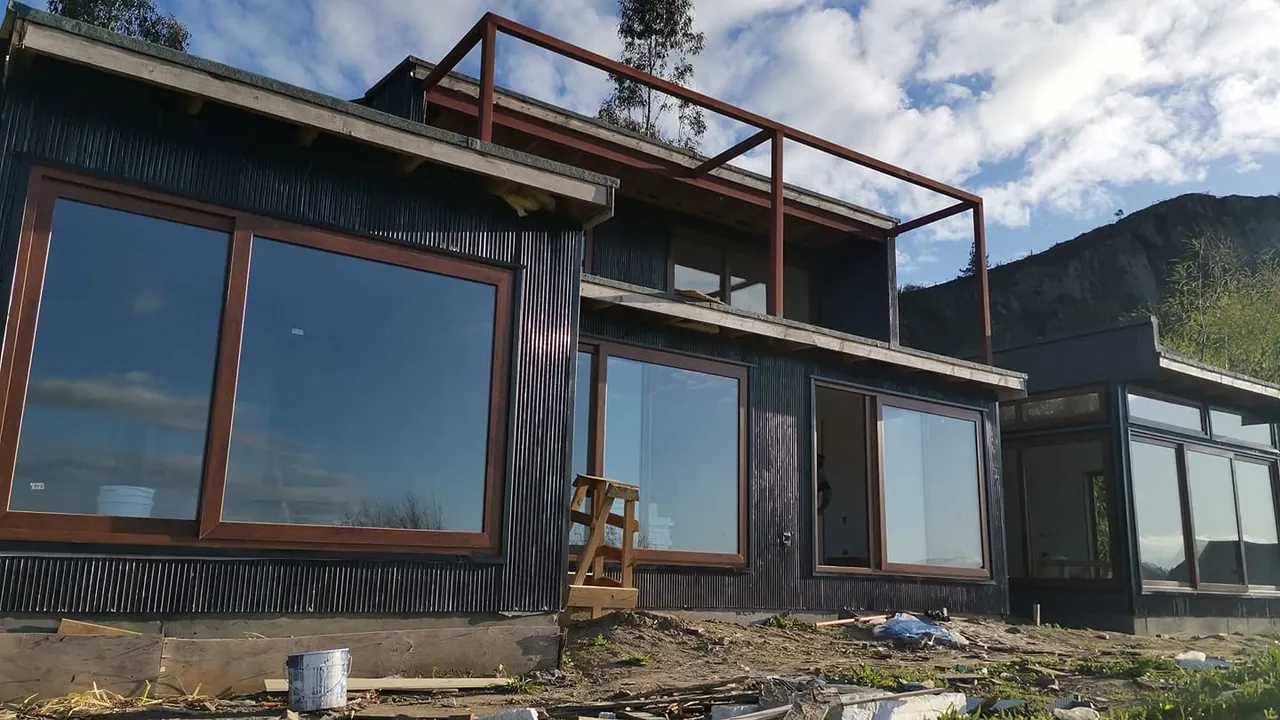 Ventanas de marco café en la fachada oscura de una casa en parcela en Laja.