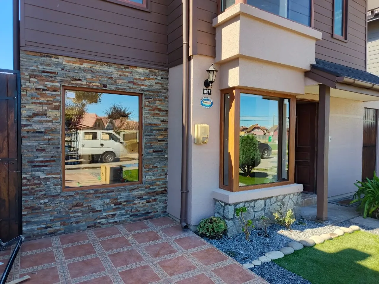 Ventanas de una vivienda con fachada de piedra y muros claros en Concepción.