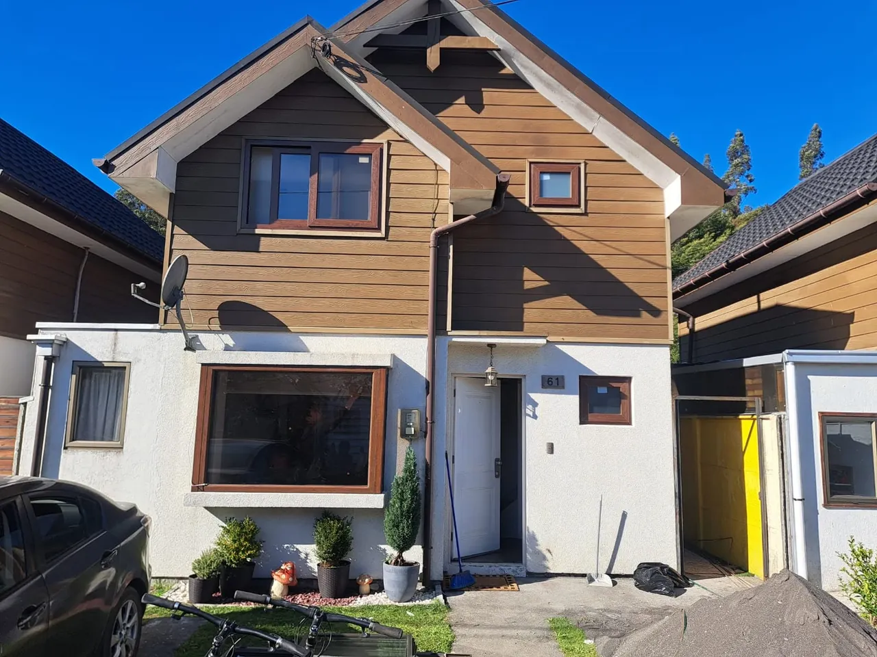 Fachada de una casa familiar de dos pisos con ventanas de marco café en Nonguén, Concepción.